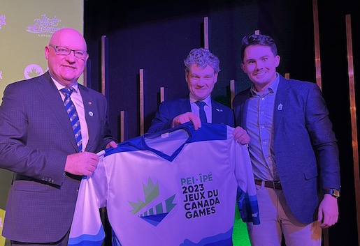 UPEI President Keefe is presented with a 2023 Canada Games jersey by Jonathan Ross, Volunteer VP, Sponsorship and Revenue Generation, and Ethan MacFadyen, Coordinator – Sponsorship with the PEI 2023 Canada Games Host Society. photo of three men holding Canada Games jersey