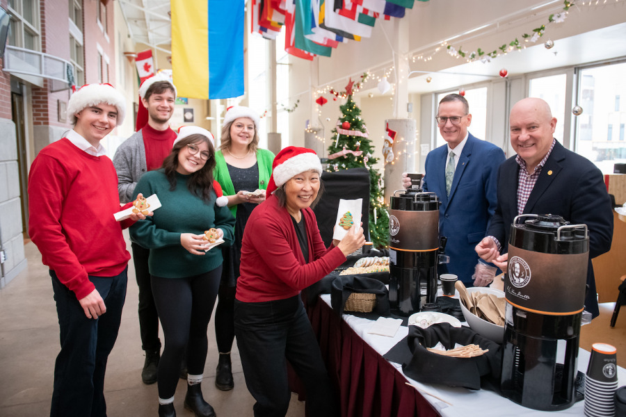 photo of students and music professor wearing Santa hats with the vice-president and president of the University