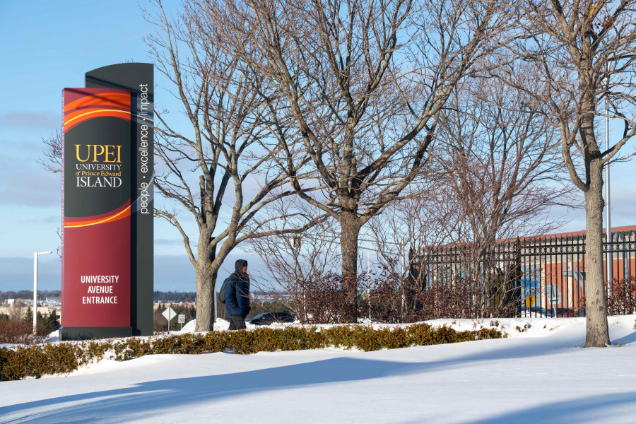 photo of student walking by UPEI sign in winter