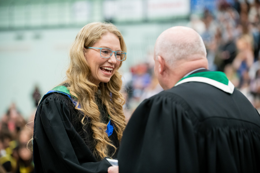 photo of graduate shaking hands with man in gown