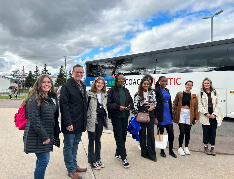 UPEI students and Vice-President Academic and Research Greg Naterer board the bus to attend "A Conversation with Michelle Obama" group of people standing in front of a bus