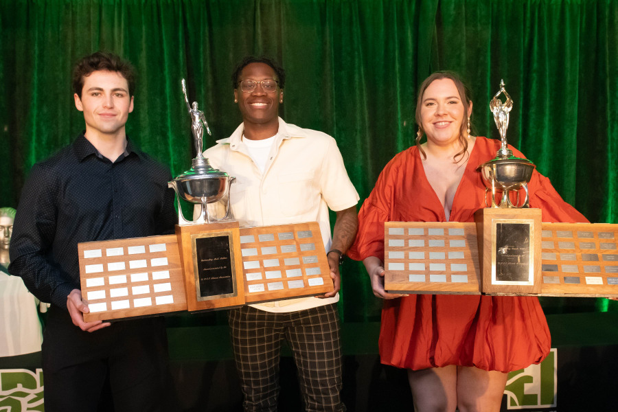 photo of three people holding large trophies