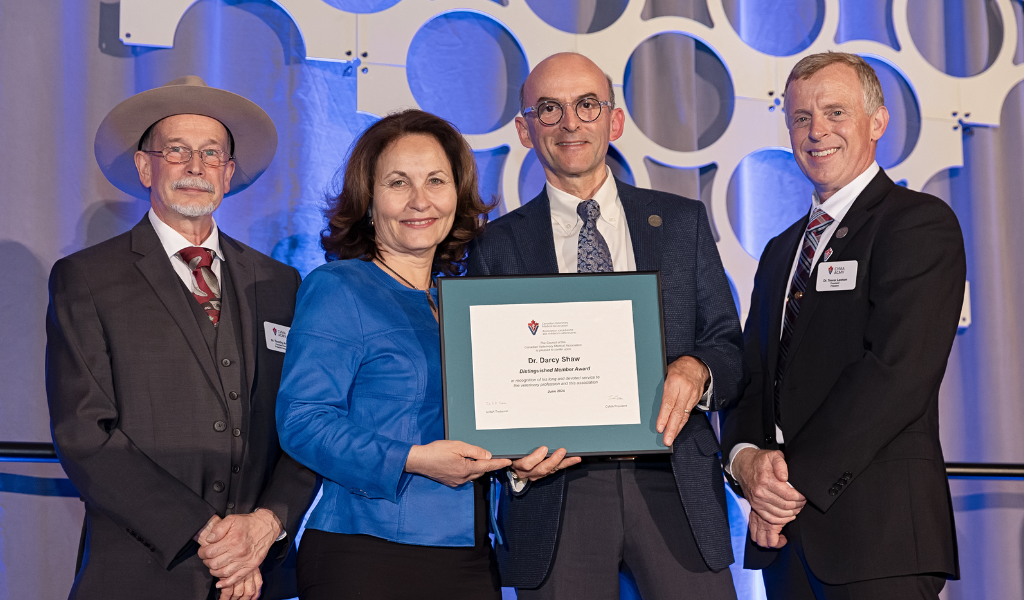 Dr. Darcy Shaw receives the Distinguished Member Award from the CVMA from Dr. Dominique Griffon, dean of the Atlantic Veterinary College. Looking on are Dr. Timothy Arthur (left), president of the CVMA, and Dr. Trevor Lawson (right), past-president of the CVMA. Dr. Darcy Shaw receives the CVMA Distinguished Member Award