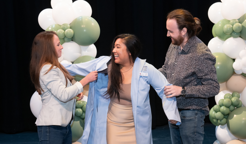 Giselle Kan, Class of 2028, receives her blue coat from her partner, Austin Gautreau, and her mentor and AVC alumna Dr. Lauren Brooks. Giselle Kan, Class of 2028, receives her blue coat from her partner, Austin Gautreau, and her mentor and AVC alumna Dr. Lauren Brooks.