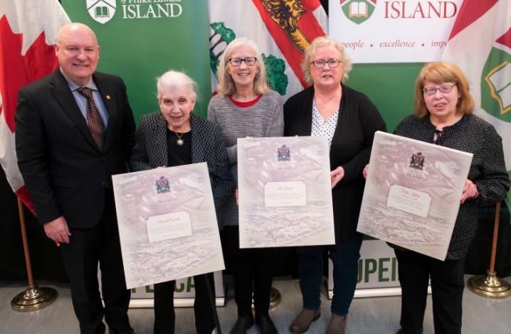 The University of Prince Edward Island named the late Merritt Crockett, founding University Librarian; the late Leo Cheverie, library technician and community advocate; and Betty Jeffery, Librarian Emerita, as its 2023 Founders. Dr. Greg Keefe, then interim president, congratulates (L-R) Mrs. Mariedith Crockett, who accepted on behalf of Mr. Crockett; Karen Cheverie-Bergeron and Irene Power, who accepted on behalf of Mr. Cheverie; and Ms. Jeffery. photo of of five people standing holding three plaques