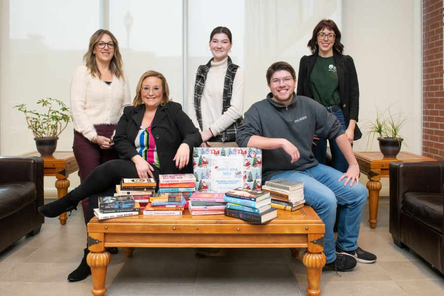 Displaying books already collected for the book drive for clients of the PEI Provincial Addiction Treatment Centre are Leslie Warren, director of acute and complex care, Mental Health and Addictions, Health PEI; Sherri Lannigan, volunteer services coordinator for acute and complex care, Mental Health and Addictions, Health PEI; Marie Thibault-Messier and Andrew Clow, UPEI nursing students; and Sydney Gaudet, assistant professor, UPEI Faculty of Nursing. People with books