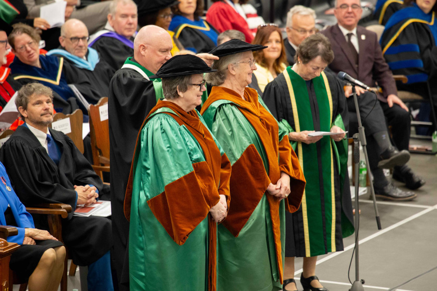 Mary Jeanette Gallant and Aggi-Rose Reddin were two of five people awarded honorary degrees from UPEI during Convocation ceremonies in May 2024 Photo of a man placing a hat on a woman at a convocation ceremony