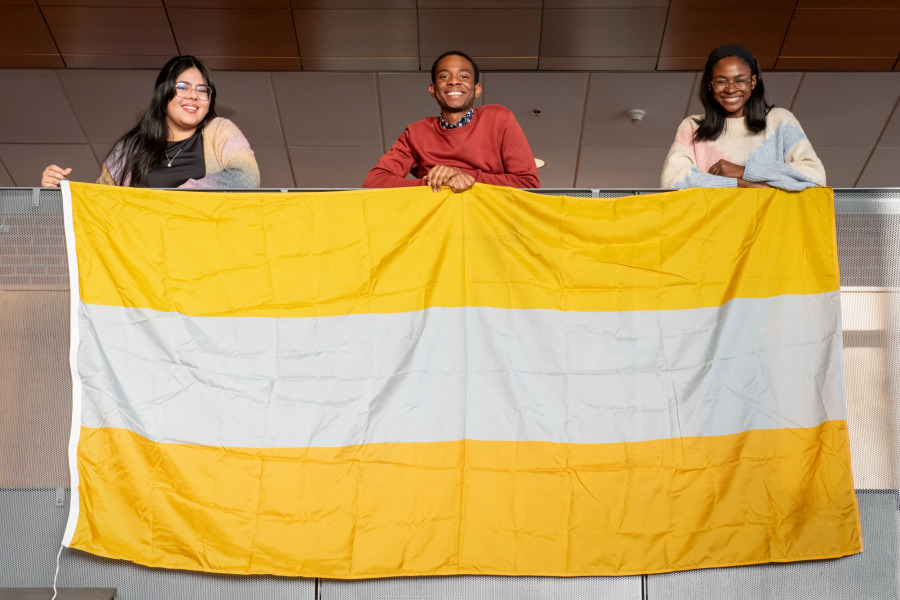 UPEI students Luciana Quiroa Paredes, Obed Oluwakoya, and Anthonia Bebiem display the UN's Flag of the Rights of Persons with Disabilities on December 3--the International Day of Persons with Disabilities. They have organized a campus-wide event on January 13, 2025, to raise awareness about and advocate for improved accessibility on campus. Students with flag