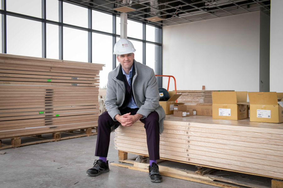 Paul Young in Faculty of Medicine building man with hardhat on sitting on materials on construction site