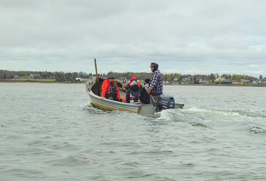Robbie Moore (standing), owner of the Brackley Bay Oyster Company, takes UPEI students on a tour of his lease in Brackley Bay. UPEI students on boat