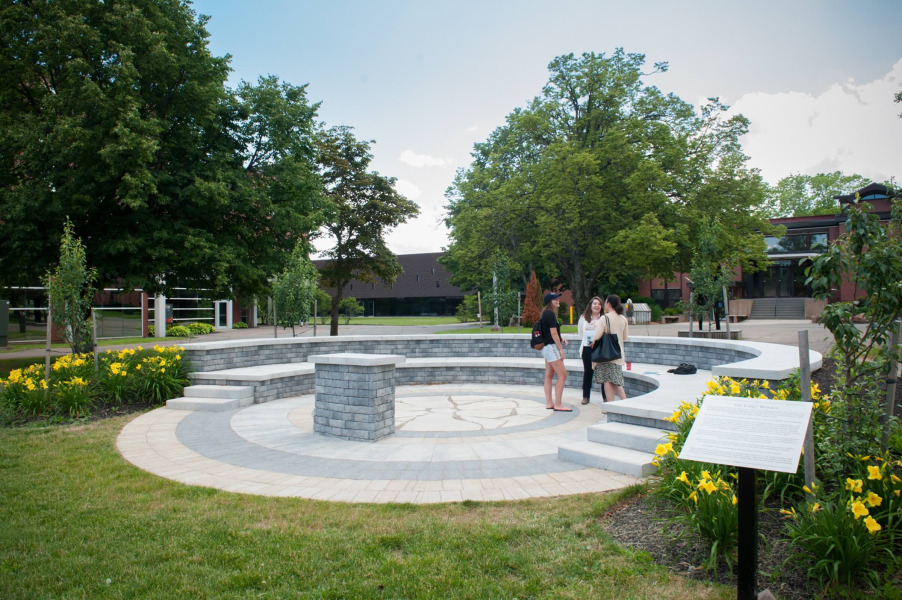 Photo of three students standing in an outdoor amphitheatre on campus