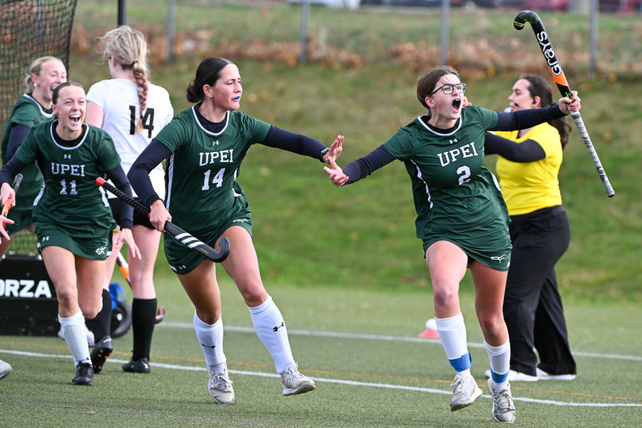 UPEI Field Hockey Panthers Jenaya Ross (#11) and Kali Smith (#14) help Kayla Batchilder (#2) celebrate her game-winning goal against Dalhousie University which secured a U SPORTS bronze medal for the team on home turf.
