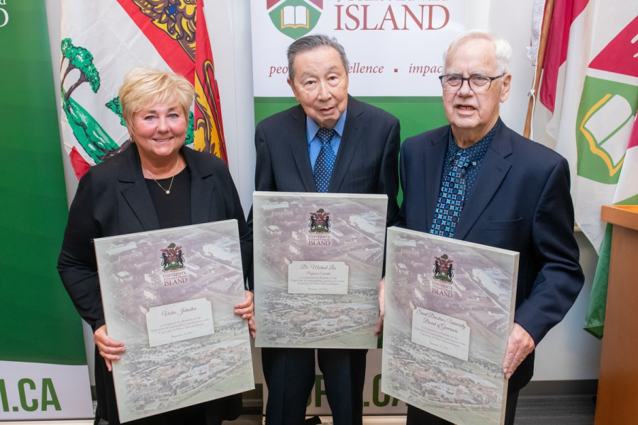 photo of three people holding canvas framed certificates