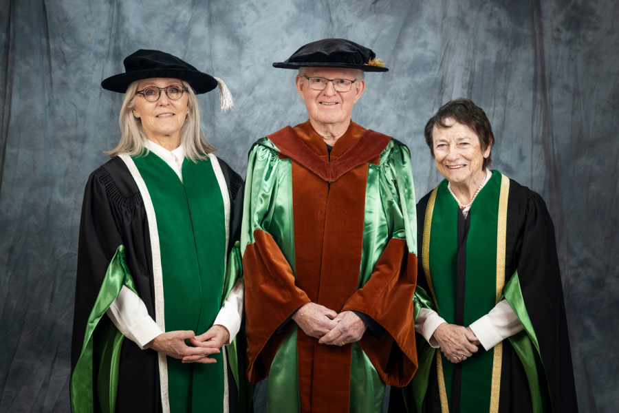 Photo of three people wearing academic regalia