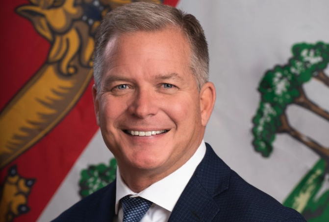 Photo of man smiling with PEI flag in background