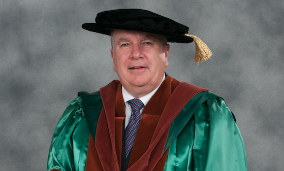 Photo of man wearing academic regalia and hat