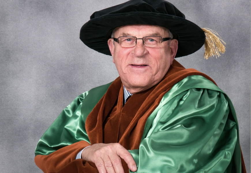 Photo of man wearing glasses and academic regalia