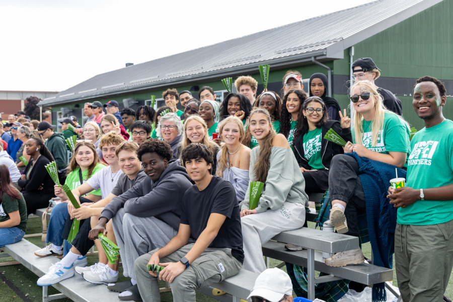 photo of smiling students sitting on bleachers