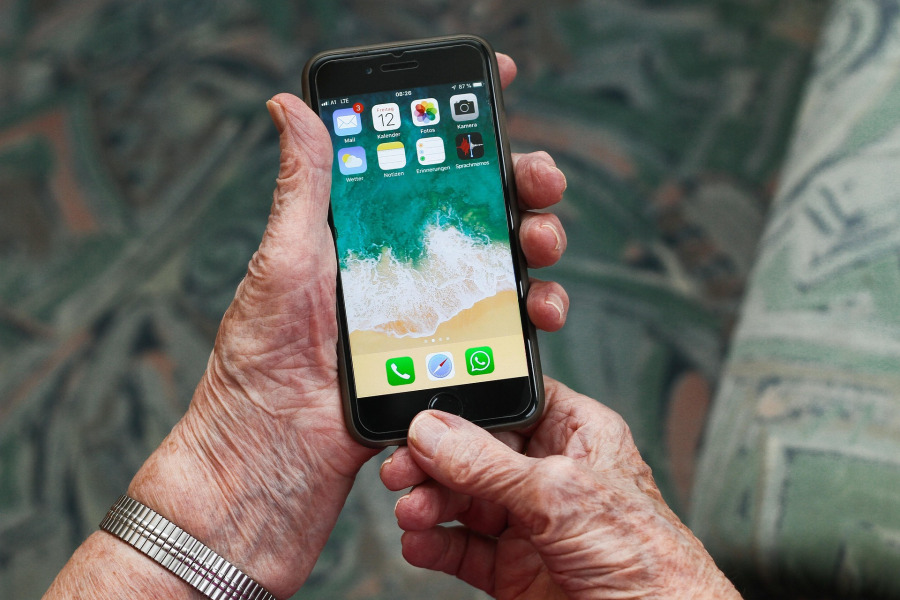 Senior holding phone showing apps