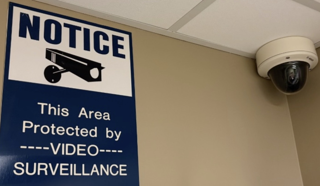 photo of a security camera alongside a sign with a notice