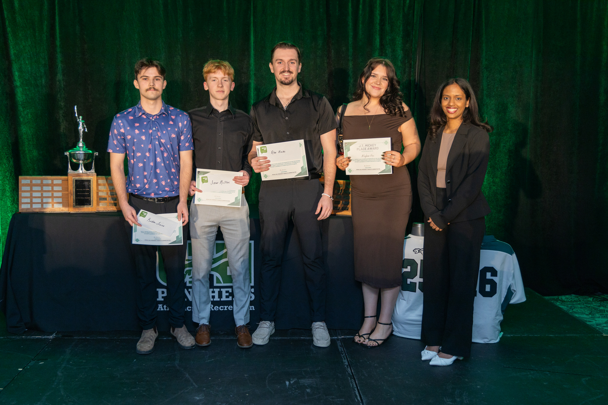 Photo of five people, some holding certificates, in front of a table backdrop