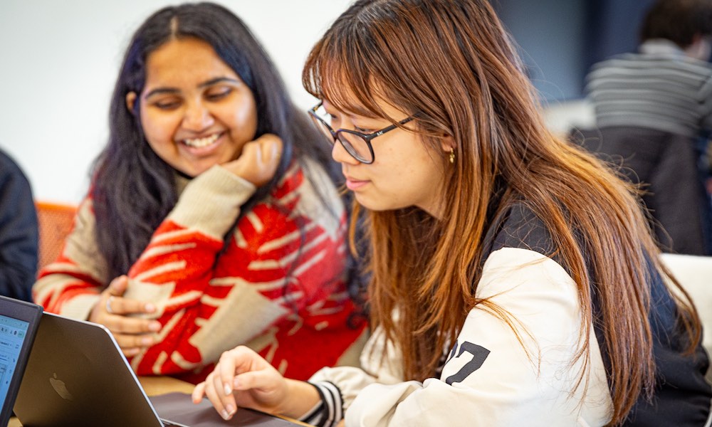 two students looking at a laptop screen