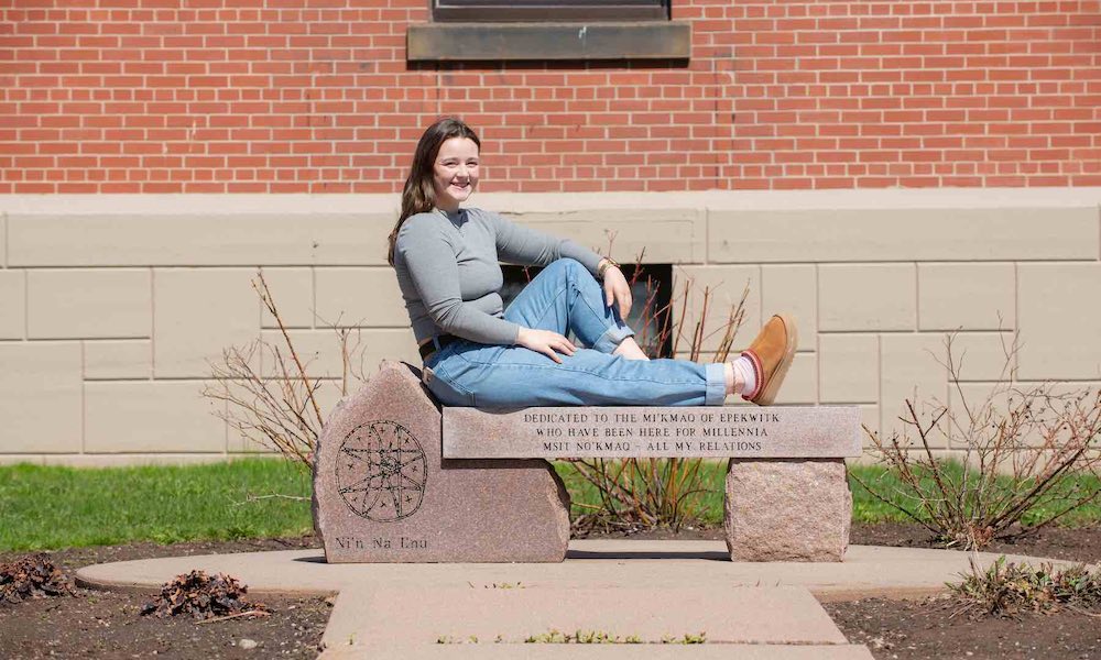 UPEI student Annika Masters sitting on a stone bench