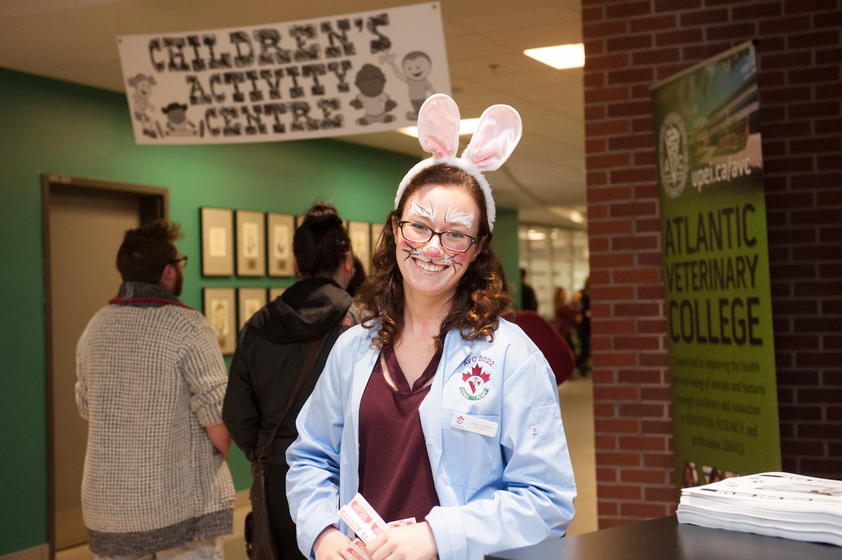 a veterinarian with face-painted whiskers wearing bunny ears
