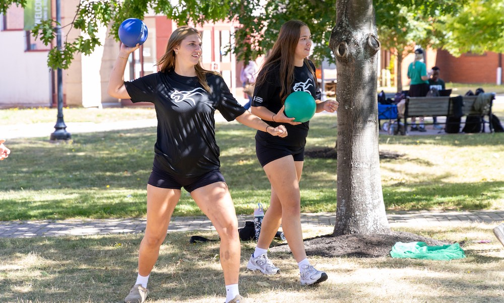two students throwing a ball in the quad