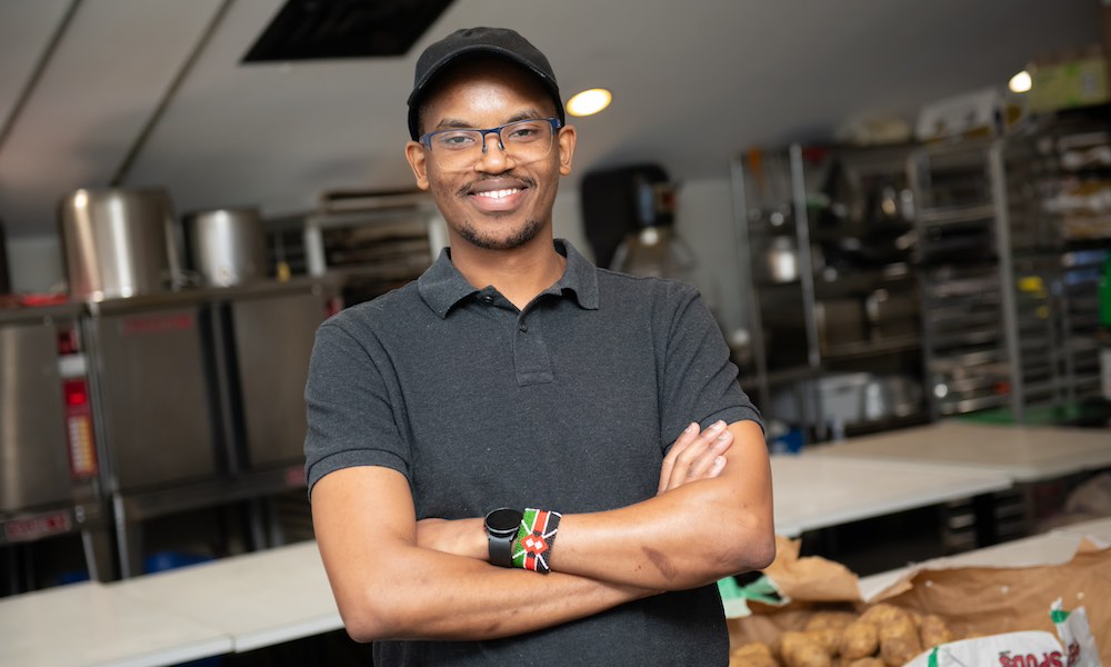a smiling man with arms folded in a restaurant kitchen