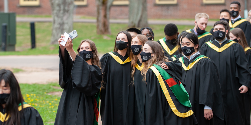 students in graduation gown taking a self-photo