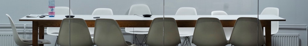 a boardroom table with 12 white empty chairs