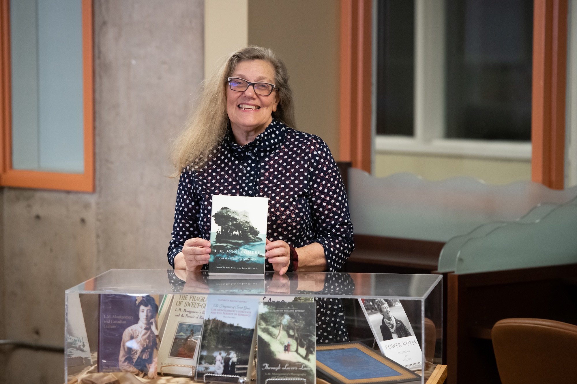 dr. jean mitchell in upei's robertson library holding a book she has written