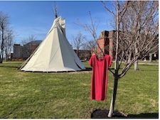 a red dress in a tree beside a tipi