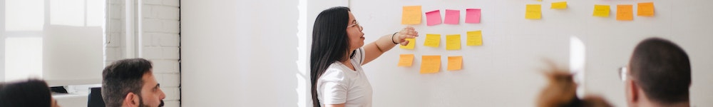an instructor placing coloured post-it notes on a whiteboard