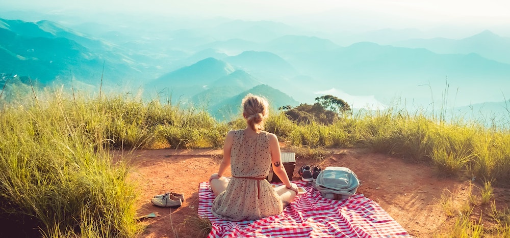 a student sitting on a blanket overlooking a valley and mountains in Costa Rica
