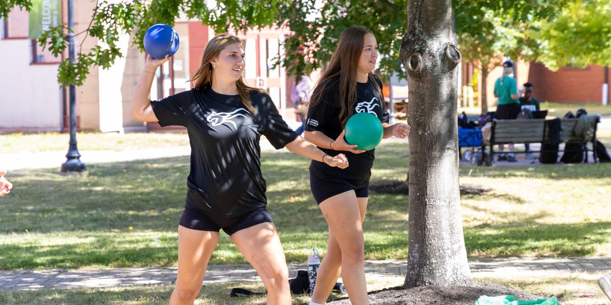 two students in the quad throwing balls