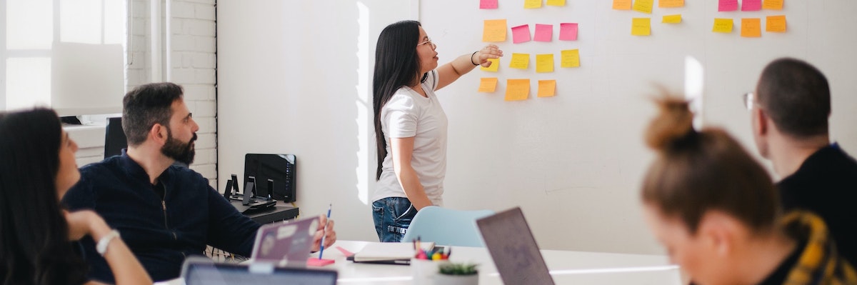 a facilitator using coloured post-it notes on a whiteboard