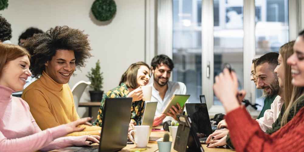 a group of people sitting at a table using laptop computers
