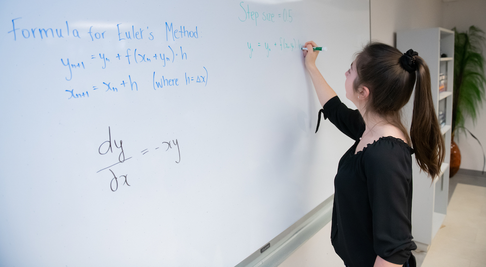 upei math graduate shannan hill writing on a whiteboard