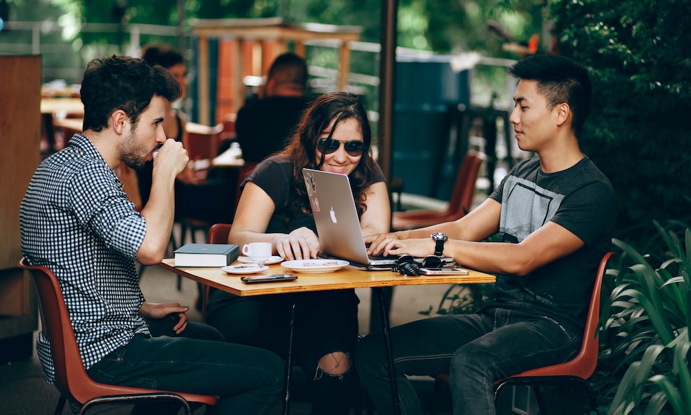 three students at a cafe studying and laughing