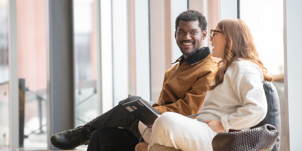 two people talking by large windows