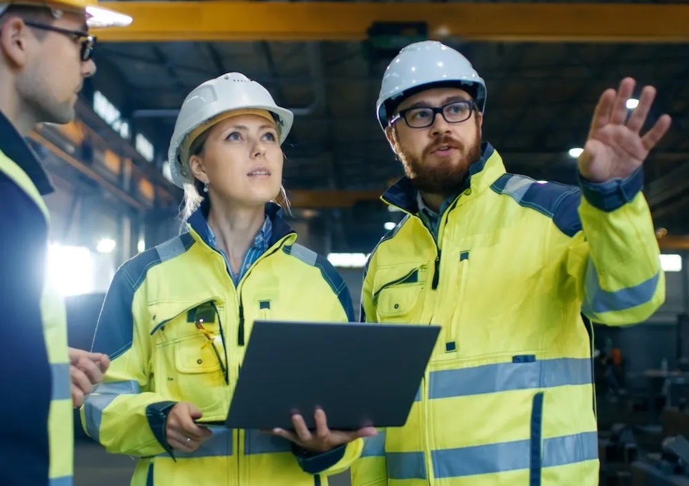 three workers in hardhats looking at a worksite