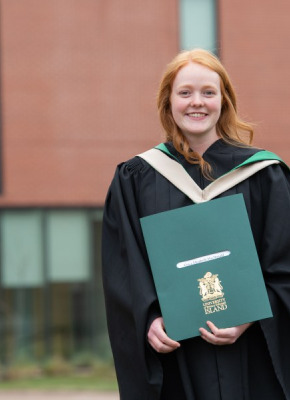 Photo of female graduate holding her degree on the UPEI campus