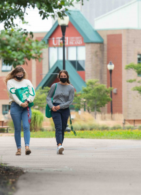 photo of two women walking on campus wearing masks