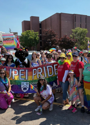 Photo of large group of people wearing rainbow colours 