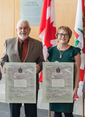 Photo of four people standing in a group, three of them holding canvas recognition frames