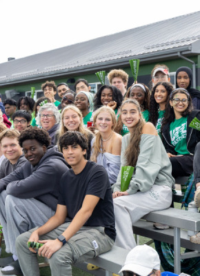 photo of smiling students sitting on bleachers