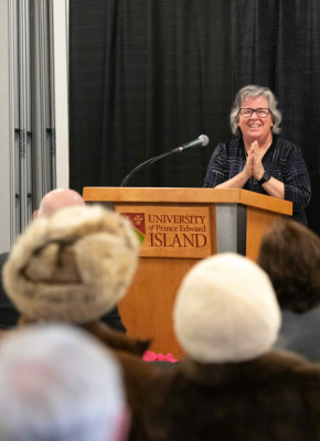 Woman standing at podium with hands clasped