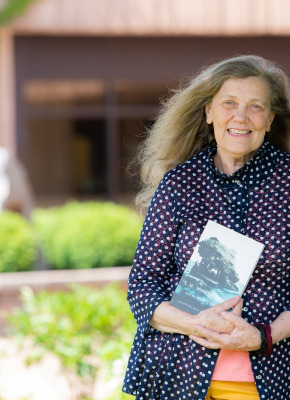 dr. jean mitchell photographed outside beside a tree, holding her book 